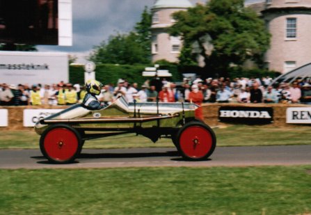 1909 Ford Model T - A 1909 Ford Model T speedster with red wheels drives past spectators.