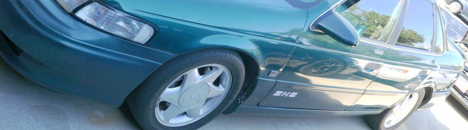 Green 1993 Ford Taurus sedan, front quarter view, showing headlight, wheel, and side panel