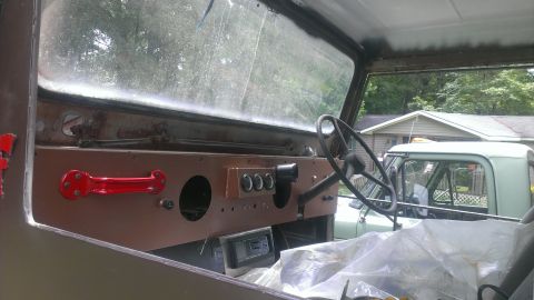 1978 Ford Bronco - The interior of a Jeep CJ shows its dashboard and steering wheel, with another vehicle parked outside.