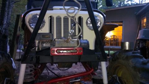 1978 Ford Bronco - This modified Jeep CJ-5 features a prominent winch and off-road tires, set against a wooded backdrop.