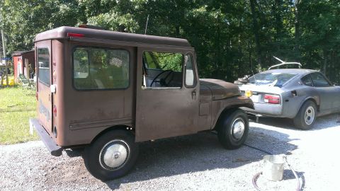 1978 Ford Bronco - Jeep FC-150 Forward Control truck towing a Nissan 240Z in a wooded area.