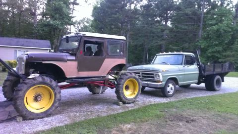 1978 Ford Bronco - A heavily modified Jeep CJ-5 with large tractor tires is parked next to a 1970 Ford F-Series flatbed truck.