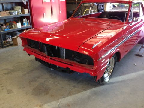 1964 Ford Fairlane - A red 1964 Ford Fairlane is parked in a garage, its front grille and bumper removed for work.