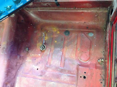 1964 Ford Fairlane - The interior floor pan shows signs of rust and wear, with a chrome handle visible.