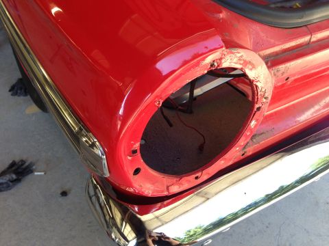 1964 Ford Fairlane - The rear of a red 1964 Ford Fairlane shows a missing tail light assembly and chrome bumper.