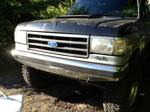 1989 Ford Bronco - Front view of a Ford truck, showing the grille, headlights, and bumper with a '4x4' decal.