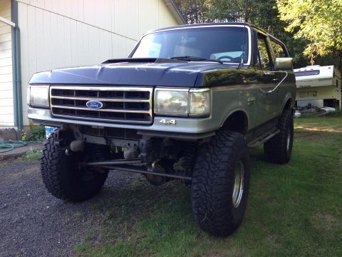 1989 Ford Bronco - This lifted Ford Bronco features a two-tone paint scheme and prominent 4x4 badging on the front fender.