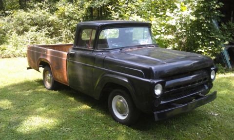 1957 Ford F-100 - This 1957 Ford F-100 pickup truck is parked outdoors on a grassy area with trees in the background.
