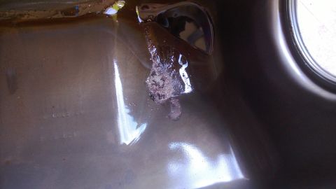 1994 Ford Bronco - Close-up of a corroded engine oil pan with visible rust and debris, marked with a SuperMotors watermark.