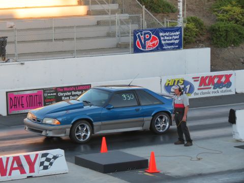 1990 Ford Mustang - A blue 1990 Ford Mustang is on a drag strip, with a person standing nearby.