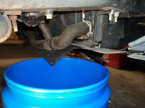 2004 Mercury Grand Marquis - Underbody view of a vehicle with hoses and a blue bucket collecting fluid. Text on bucket reads SUPERMOTORS.