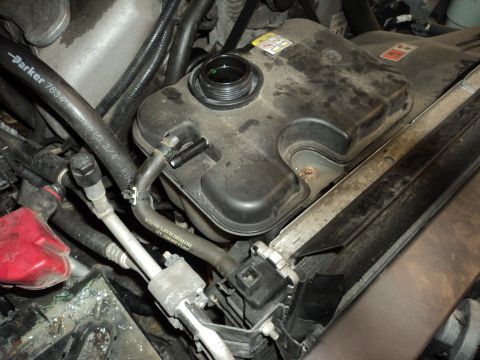 2004 Mercury Grand Marquis - Close-up of a vehicle's engine bay, focusing on the coolant reservoir and surrounding hoses.