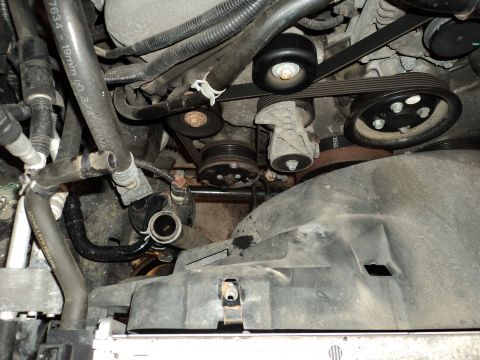 2004 Mercury Grand Marquis - Close-up view of an engine bay, focusing on the serpentine belt system and associated hoses. Some text is visible on a hose.