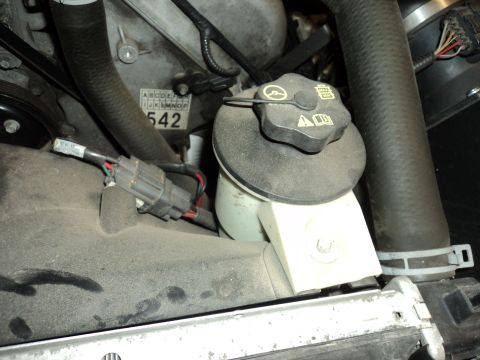 2004 Mercury Grand Marquis - Close-up view of an engine bay, showing the coolant reservoir, hoses, and a label with the number 542.