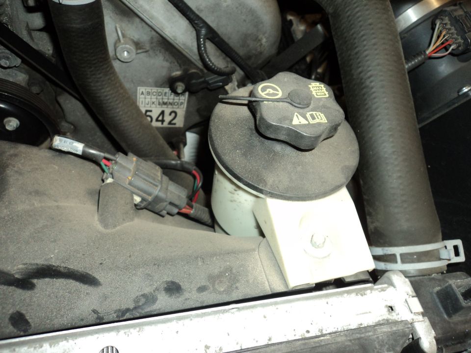 Engine bay with coolant reservoir, hoses, and a label with '542'