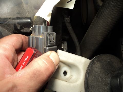 2004 Mercury Grand Marquis - A hand uses a red screwdriver to manipulate an automotive electrical connector.