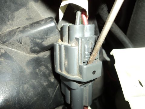 2004 Mercury Grand Marquis - Close-up of a gray electrical connector being worked on with a screwdriver.