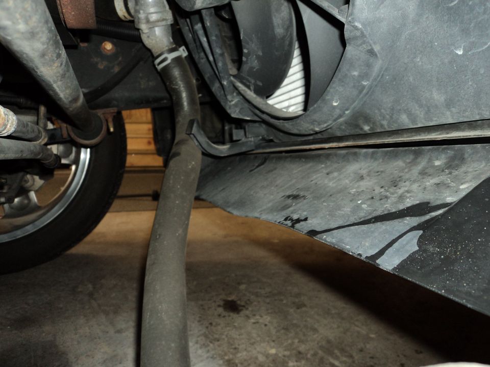 car's underbody showing a hose, radiator fan, and part of a tire