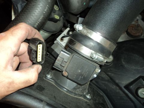 2004 Mercury Grand Marquis - A hand disconnects a sensor from the air intake system, likely for maintenance or repair.