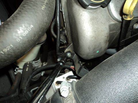 2004 Mercury Grand Marquis - Close-up view of an engine bay, showing a wrench being used on a bolt, with a hose visible that has part numbers printed on it.