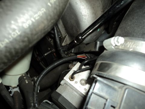2004 Mercury Grand Marquis - Engine bay detail showing ABS module, hoses, and a tool working on a bolt.