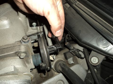 2004 Mercury Grand Marquis - Close-up of a hand manipulating the throttle linkage on a vehicle's engine.