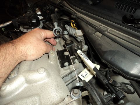 2004 Mercury Grand Marquis - Close-up of engine bay components, including a hand manipulating a throttle cable and labeled wires for 'Connector' and 'Fuel'.