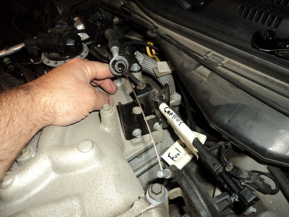 Hand adjusting throttle cable in engine bay with labels 'Connector' and 'Fuel'