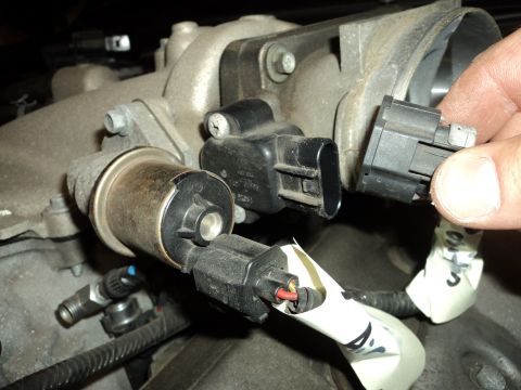 2004 Mercury Grand Marquis - Close-up of engine components, showing electrical connectors and a hand disconnecting one.