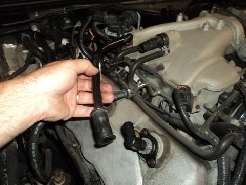 2004 Mercury Grand Marquis - A hand holds a black engine component near the intake manifold of a vehicle's engine.