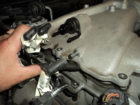2004 Mercury Grand Marquis - Close-up of an engine's intake manifold and fuel lines, with a hand obscuring some wiring.
