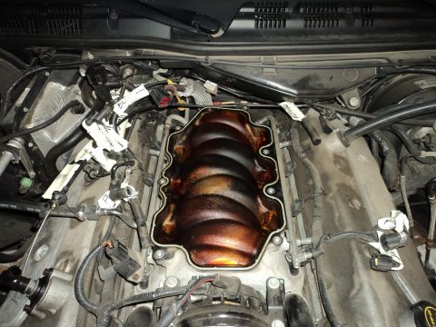 2004 Mercury Grand Marquis - Close-up view of an engine bay with the intake manifold removed, revealing internal engine parts and associated wiring harnesses.