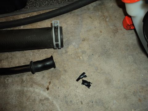 2004 Mercury Grand Marquis - A damaged hose and clamp lie on the concrete floor, with a small piece of black tape nearby.