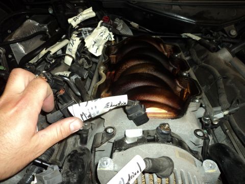 2004 Mercury Grand Marquis - Close-up of an engine bay with a hand holding a wire labeled 'Miles Electric'.