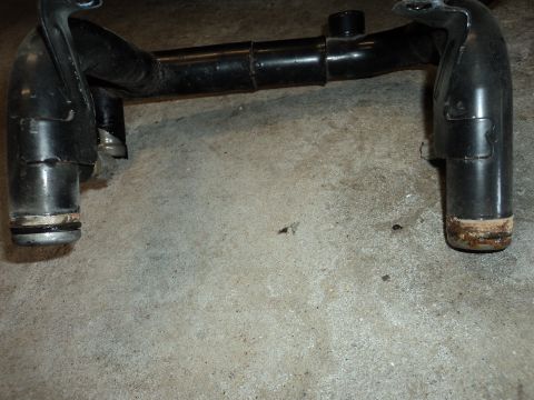 2004 Mercury Grand Marquis - Close-up of a black metal automotive part with visible rubber seals on its ends, placed on a concrete surface.