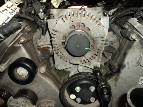 2004 Mercury Grand Marquis - Close-up view of an alternator and engine components, with a socket wrench attached.