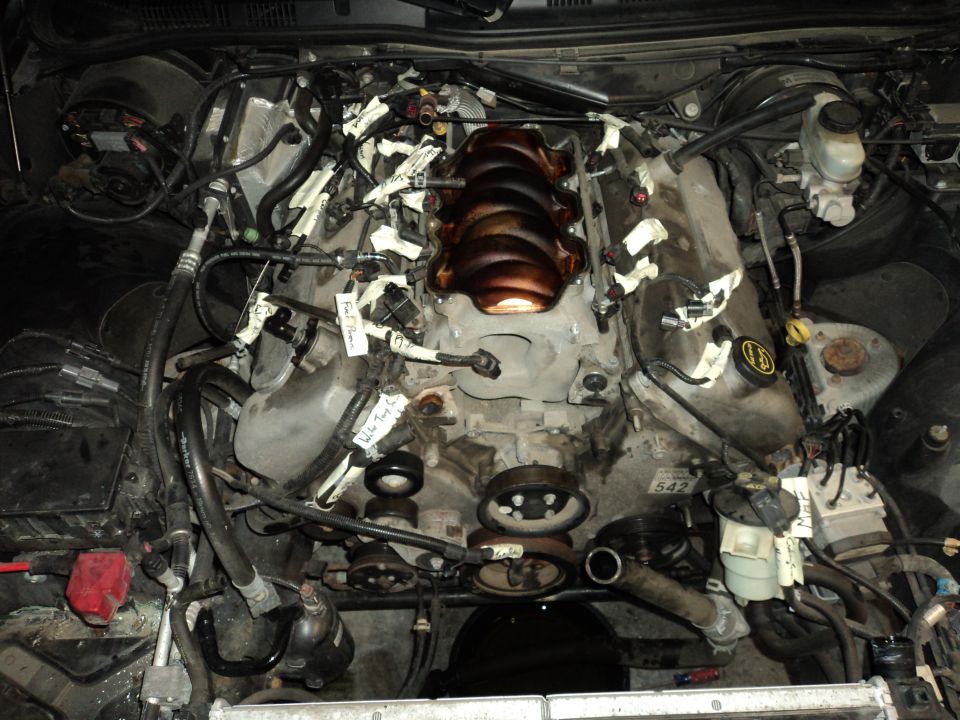 Engine bay with intake manifold removed, wires taped off. Some labels visible
