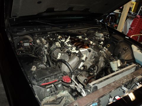2004 Mercury Grand Marquis - The engine compartment of a car is shown with the hood raised, revealing the engine and its components.