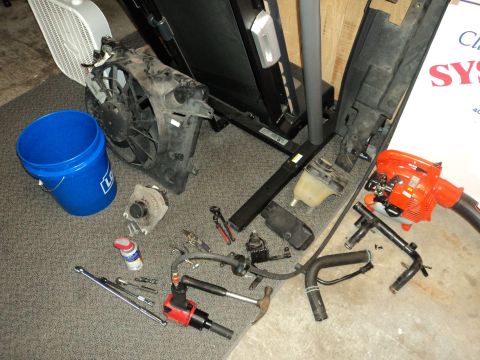 2004 Mercury Grand Marquis - Various car parts and tools are laid out on a carpeted floor, possibly for a repair or swap.