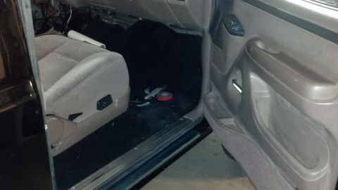 1995 Ford Bronco - The interior of a vehicle shows the passenger seat and door panel, with some tools on the floor.