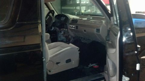 1995 Ford Bronco - The interior of a black SUV is visible, with the dashboard and seats exposed, suggesting ongoing work or repair.