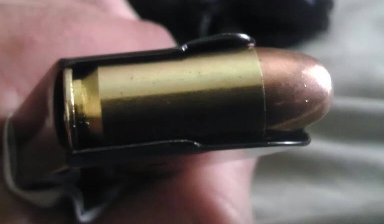 Close-up of a bullet in a magazine clip, held by a hand