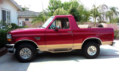 1994 Ford Bronco - This 1994 Ford Bronco features a two-tone red and tan paint scheme and a removable top, offering an open-air driving experience.