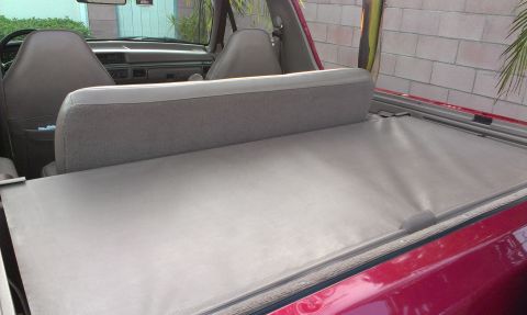 1994 Ford Bronco - The interior of a red SUV shows tan seats and a tonneau cover, suggesting an earlier model year than claimed.