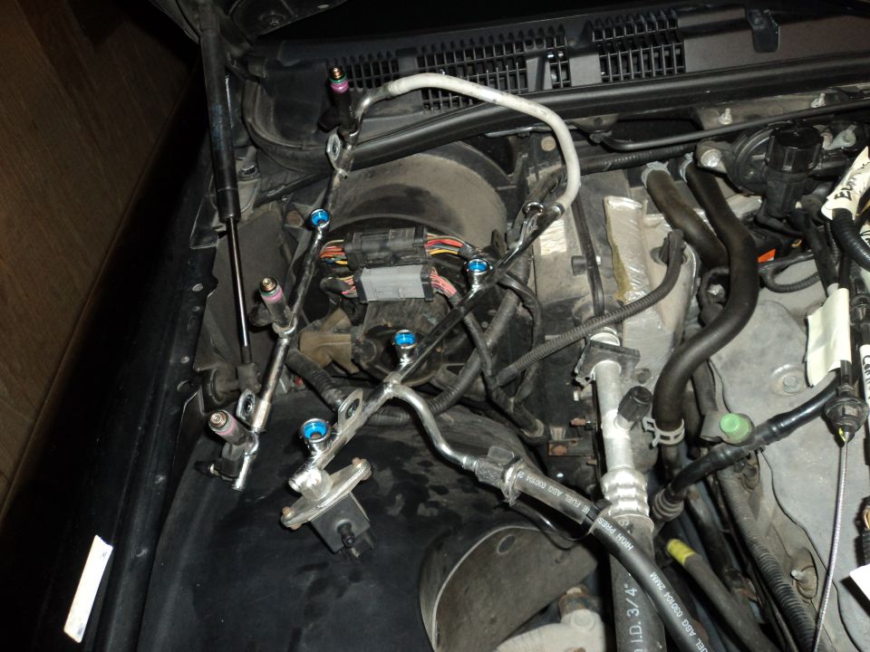 Engine bay showing fuel rail, injectors, and various hoses and wiring