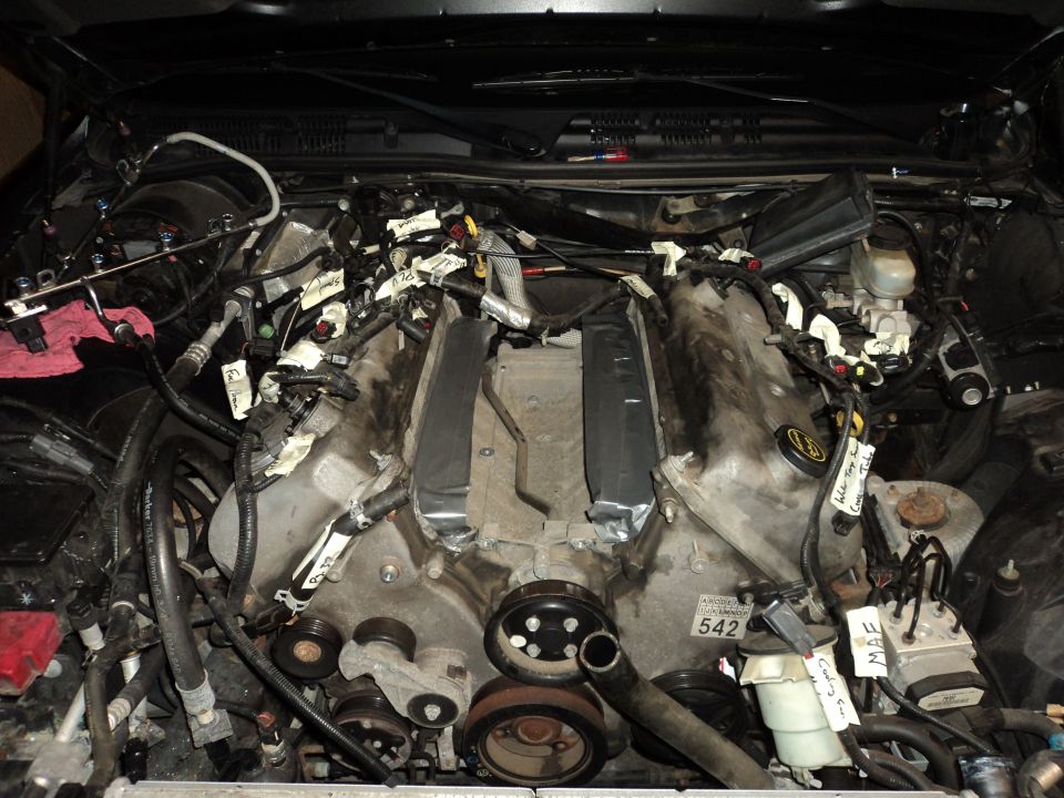 Engine bay with V8 engine exposed, wiring harnesses labeled with tape