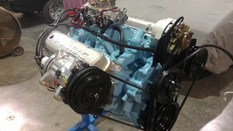 1972 Pontiac Trans Am - A Pontiac V8 engine is displayed on a stand, blue block paint and silver valve covers with 'Pontiac' lettering.