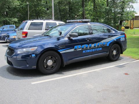 2001 Ford Crown Victoria - A Kingston police car is parked in a lot next to other vehicles.
