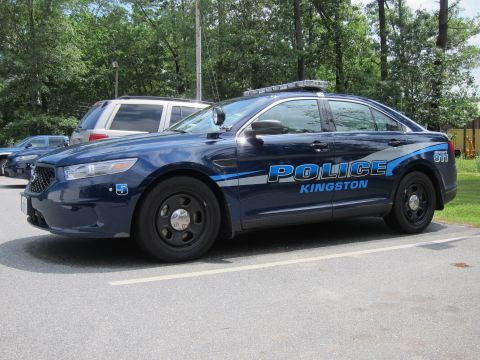 2001 Ford Crown Victoria - A dark blue police car with emergency lights on the roof is parked in a lot.