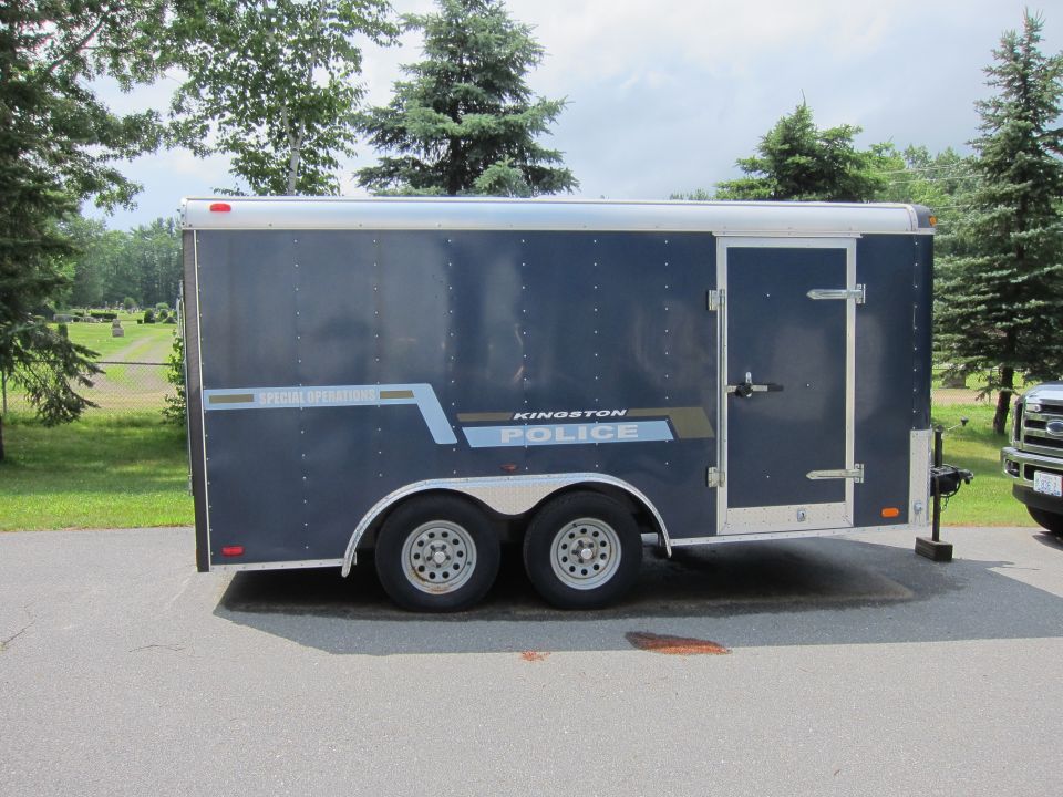 Dark blue trailer with "KINGSTON POLICE" text on its side